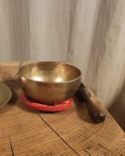 Klangschale mit hölzernem Klöppel auf einer Holzplatte